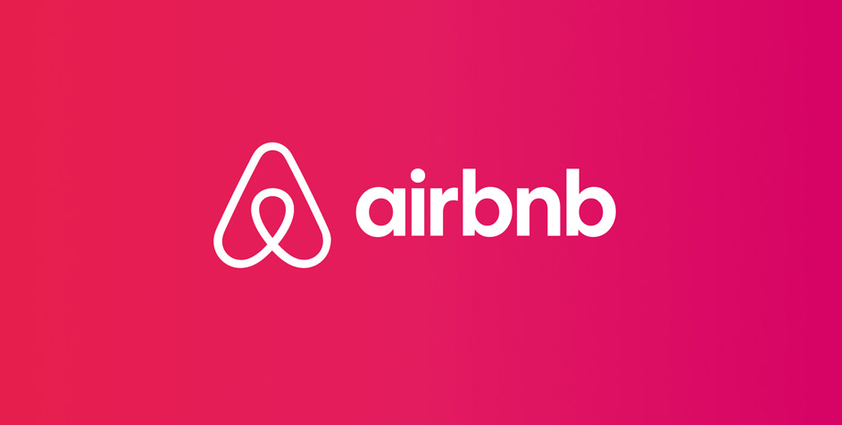 Image shows Airbnb logo set against a vibrant pink background.